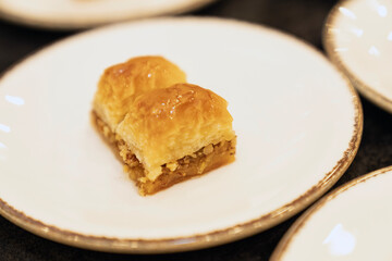 Traditional Turkish Baklava Dessert with Honey and Nuts on White Plate . Authentic Middle Eastern Sweet Pastry with Flaky Layers, Syrup Glaze, and Rich Nut Filling. Close up Food Photography