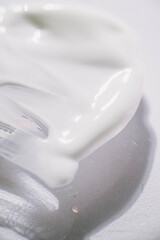 Minimalist macro photography for beauty, dermatology, and cosmetic industry concepts. Close-up of white cream texture smeared on a surface. Skincare and cosmetic product background showing moisturizin
