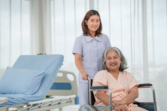 Asian nurse pushing senior female patient in a wheelchair at the hospital ward