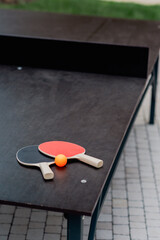Table tennis paddles and orange ball on a playing table.