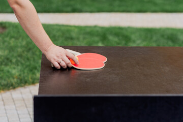 Table tennis paddles and orange ball on a playing table.