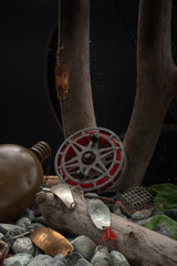Vintage Soviet fishing gear with an old reel and predator lures placed on stones and wooden branches.