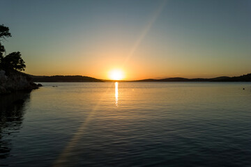 Idyllic Sunset Over Serene Sea with Rocky Coastline and Pine Trees. Tranquil Nature Landscape, Golden Hour, Calm Water, Peaceful Scenery, Travel Destination, Coastal View, Summer Evening Vibes