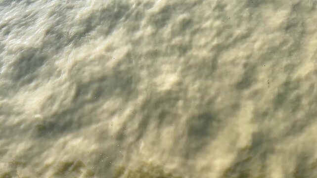 Murky floodwater. Close-up of a dirty, polluted river current, a symbol of environmental disaster or contamination.Top-down view of a strong current carrying silt and sediment