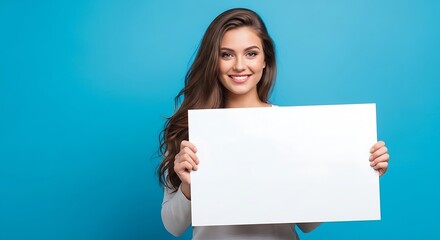 Smiling woman holding a blank white sign against a blue background, looking at the camera.