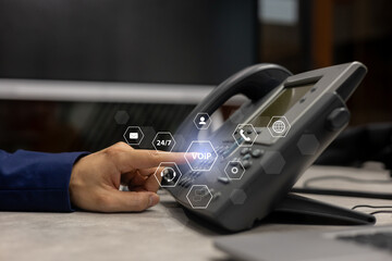 close up employee call center man hand point and press button number telephone voip machine in the office desk with virtual icon of communication technology for business and contact us concept