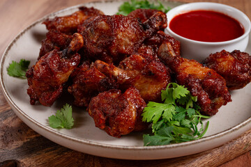 Juicy fried chicken pieces, served with spicy dipping sauce, on a rustic wooden table,
