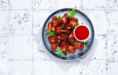 Crispy pieces of fried chicken, on a plate with sauce and herbs, in a modern kitchen environment, there are no people