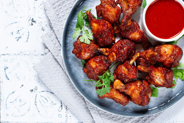 Crispy pieces of fried chicken, on a plate with sauce and herbs, in a modern kitchen environment, there are no people