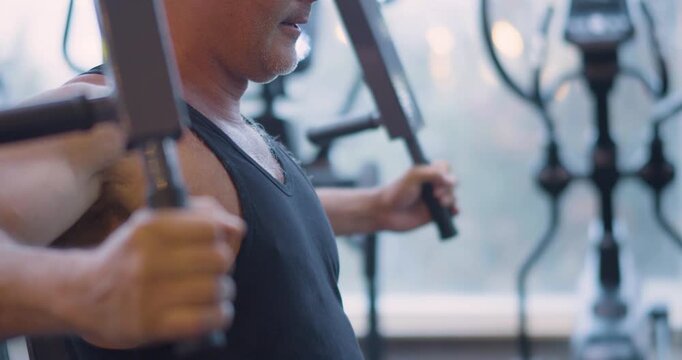 Gym workout. Butterfly exercise. Middle aged Caucasian man trains his pectoral muscles in the gym. Gym workout shows man targeting pectorals through butterfly machine exercise.