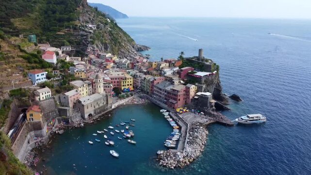 Aerial view of Vernazza, one of the five villages of Cinque Terre, showcases its vibrant architecture and picturesque harbor with boats docked along the shore