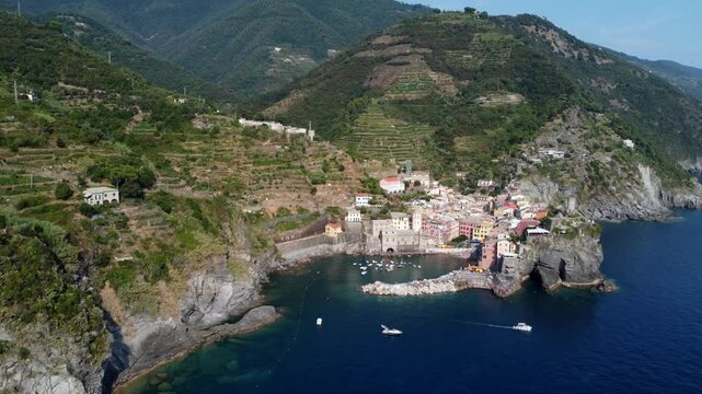 Aerial view of Vernazza, one of the five villages of Cinque Terre, showcases its vibrant architecture and picturesque harbor with boats docked along the shore