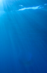 Light filtering down through blue water. Underwater sunlight in deep sea. Light viewed from blue abyss. Underwater sunlight shining deep with ripples on wave surface ocean ray, Under water background.