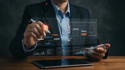 Man in suit interacting with digital interface showing gantt chart and data on wooden desk surface - Powered by Adobe