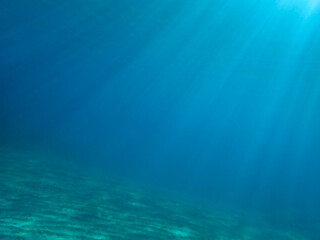 Light filtering down through blue water. Underwater sunlight in deep sea. Light viewed from blue abyss. Underwater sunlight shining deep with ripples on wave surface ocean ray, Under water background.