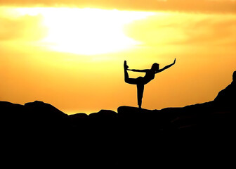 Silhouette einer Frau auf einem Berg macht Yoga bei Sonnenuntergang