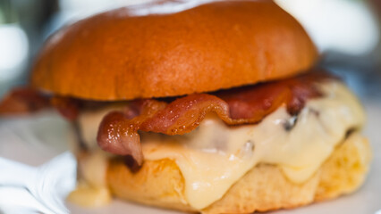 Juicy gourmet burger with crispy bacon, melted cheese, and a perfectly fried egg on top. High-quality ingredients stacked on a fresh bun, with cheese dripping and a golden yolk. Appetizing close-up fo