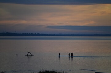 Group of children playing in shallow water in Fjellerup, Denmark at sunset