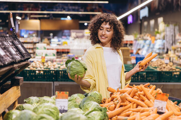 Woman Choosing between Cabbage and Carrots in Supermarket