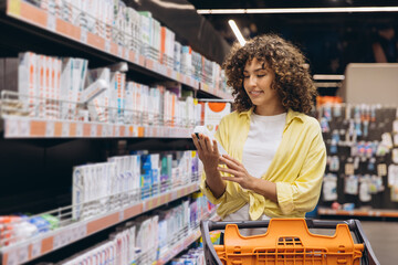 Woman choosing toothpaste in supermarket aisle