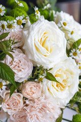 Beautiful bouquet of white roses, pink carnations, small daisies and raspberry stems. Professional flower arrangement of pastel colored buds close-up. Wedding elegant bouquet. Flower shop