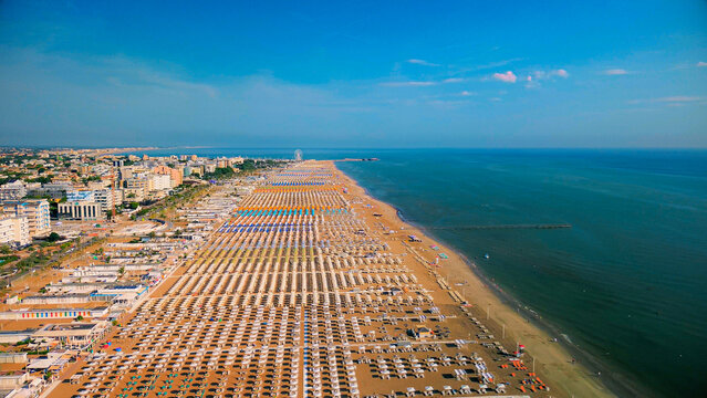Aerial view of large equipped sandy beaches. Umbrellas and sun loungers for vacationers by the sea. Vacation on the Adriatic Sea. Ferris wheel. Traveling on Europe. Vacation in Italy Rimini 21.08.2025
