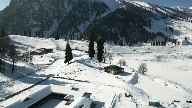 Panoramic winter drone footage of Sonmarg in Kashmir, featuring snow-covered Thajiwas mountains and sparkling white fields below.