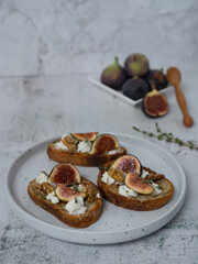 Front View Vertical of Fig Toasts with Goat Cheese and Thyme on White Plat
