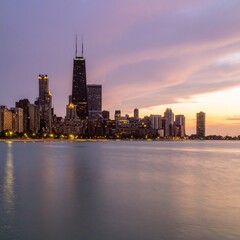 Obraz premium City skyline at sunset with glowing lights and dramatic sky
