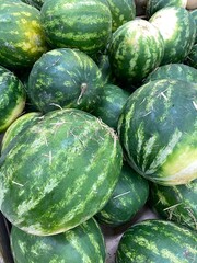 Watermelons piled together with striped green rinds, showcasing summer freshness and texture