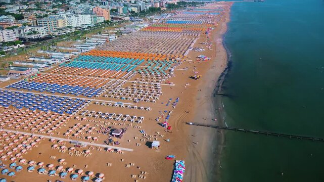 Aerial view of large equipped sandy beaches. Umbrellas and sun loungers for vacationers by the sea. Vacation on the Adriatic Sea. Ferris wheel. Traveling on Europe. Vacation in Italy Rimini 17.08.2025