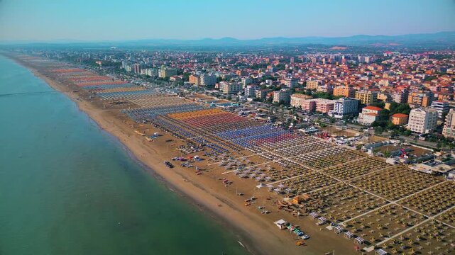 Aerial view of large equipped sandy beaches. Umbrellas and sun loungers for vacationers by the sea. Vacation on the Adriatic Sea. Ferris wheel. Traveling on Europe. Vacation in Italy Rimini 21.07.2025