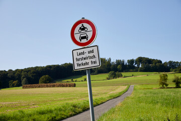 country path between fields with german traffic sign that it is closed for cars and motor bikes