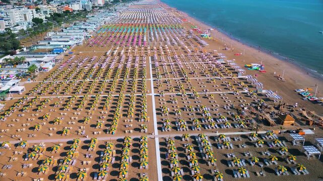 Aerial view of large equipped sandy beaches. Umbrellas and sun loungers for vacationers by the sea. Vacation on the Adriatic Sea. Ferris wheel. Traveling on Europe. Vacation in Italy Rimini 21.07.2025