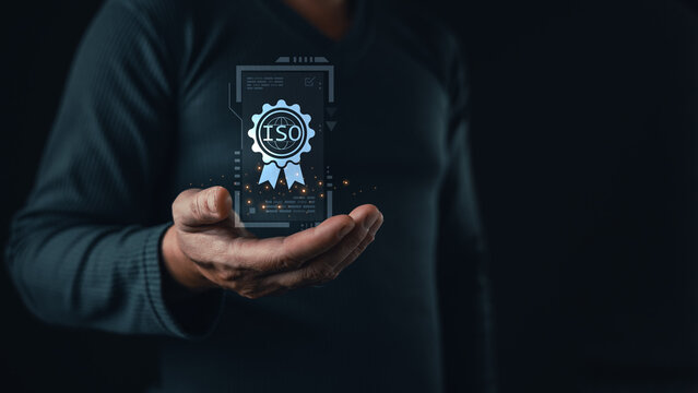 A person holds a glowing holographic certificate featuring an ISO badge, symbolizing international standards, quality assurance, compliance, and certification in modern digital business practices.