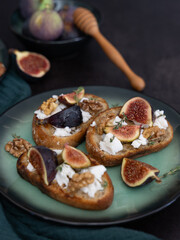 Vertical Close Up of Three Fig and Goat Cheese Toasts on Dark Background