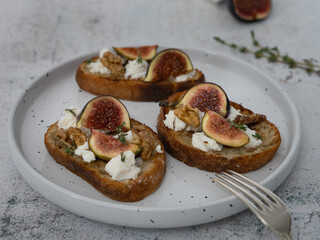 Horizontal Close Up of Fig and Goat Cheese Toasts with White Plate and Gray Background
