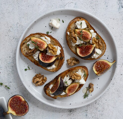 Top View of Fig and Goat Cheese Toasts on White Plate with Figs and Gray Background