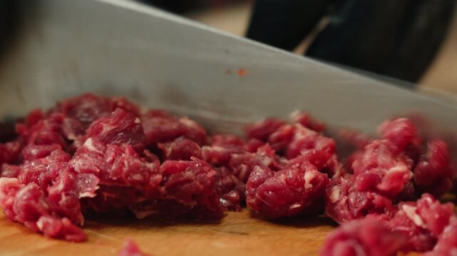 Working with beef, cut steak Chef cooking Raw beef meat tartar with sauce, man cutting steak tartare, making delicious french dish in modern restaurant. Fresh eco angus meat. 