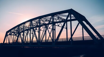 Wide shot of a steel truss bridge silhouetted against a pastel sky