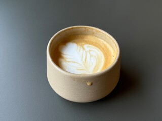 Cappuccino coffee with creamy foam served in a ceramic cup on empty table. Horizontal image in cozy cafe, perfect for menu, barista concept, breakfast mood, lifestyle blogs or drink advertising