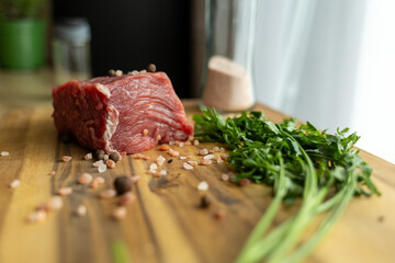 close up of a piece of fresh beef on a wooden cutting board. farm fresh meat with coarse salt and herbs on the table