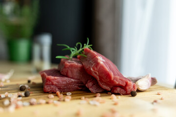 close up of a piece of fresh beef on a wooden cutting board. farm fresh meat with coarse salt and herbs on the table