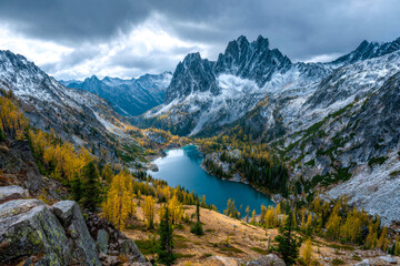 Majestic mountain lake surrounded by colorful autumn trees and rugged snow-capped peaks