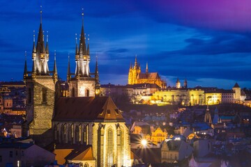 Fototapeta premium Evening view of the illuminated Church of Our Lady before Týn and Prague Castle in Prague, Czech Republic.