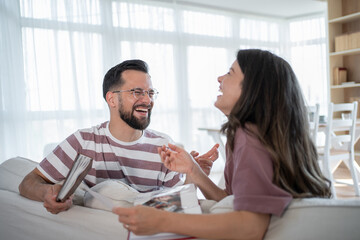 Couple laughing while looking at photo album on sofa at home