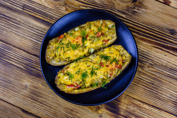 Plate with baked stuffed eggplants on a wooden table. Top view
