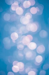 Fototapeta premium A dreamy bokeh background with glowing light orbs in soft pastel shades of blue, pink, purple, and white, blurred luminous circles floating against a vibrant blue backdrop, ethereal magical glow