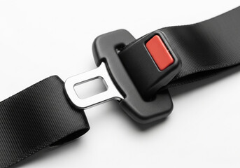 Close up of a black seat belt buckle and strap on a white background