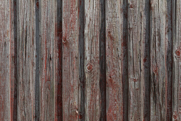 Aged wooden boards with faded red paint, rustic weathered wall surface 
